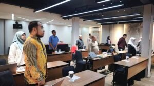 Seluruh peserta workshop berdiri menyanyikan Mars Universitas Mulia dalam suasana khidmat saat seremonial pembukaan kegiatan di Ruang Townhall Midtown Express Hotel, Rabu (30/7/2025). (Humas Universitas Mulia)