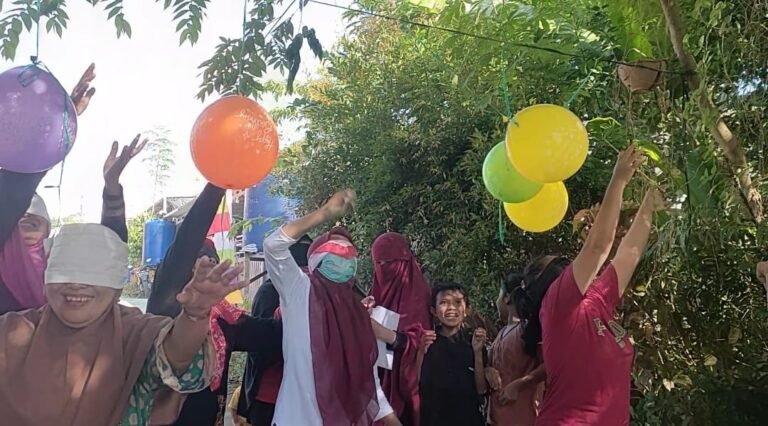 Emak-emak lomba HUT RI di Gala Puncak RT 25, Perumahan Pesona Bukit Batuah, Kelurahan Graha Indah, Balikpapan Utara, Kota Balikpapan, Provinsi Kalimantan Timur. Balon-balon warna-warni tergantung di antara pohon cery dan pagar besi hijau. Dengan mata tertutup kain merah putih, para peserta maju satu per satu, menebak-nebak arah sambil membawa sebatang tusuk bambu. (HO/Gala Puncak)